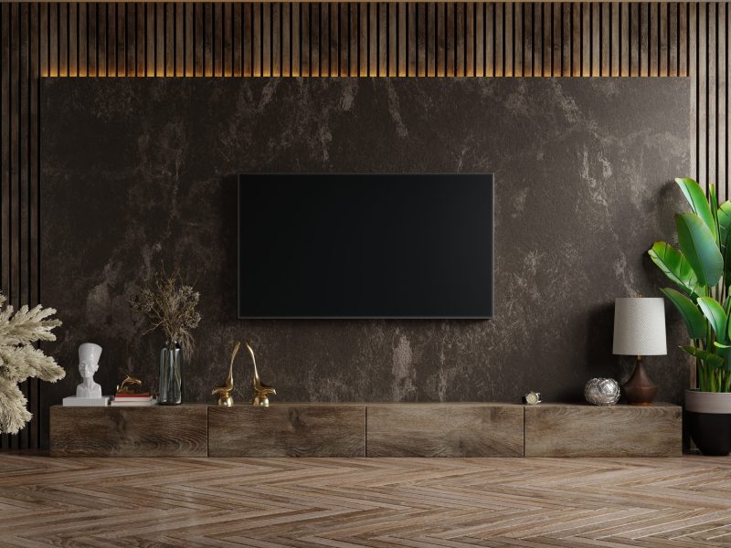Mockup a TV wall mounted in a dark room with plant on dark marble wall background,3d rendering